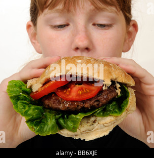 Manger une écolière beefburger avec une salade saine du remplissage Banque D'Images