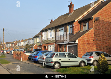 Tournant résidentiel avec des voitures garées en face de l'entrée des jardins maisons Banque D'Images