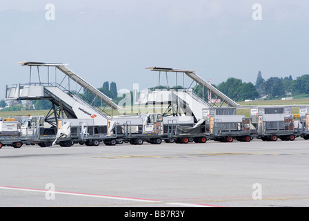 Escaliers d'avion de chariots à bagages et remorqueurs garés dans l'aire de trafic à l'aéroport de Genève Suisse Geneve Suisse Banque D'Images