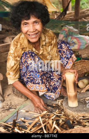 Une vieille femme prépare des segments de bambou farci de riz gluant, haricots rouges, et la noix de coco à Battambang, Royaume du Cambodge. Banque D'Images