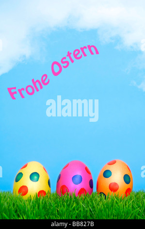 Les oeufs de Pâques colorés sur l'herbe avec ciel bleu, Frohe Ostern, joyeuses Pâques par écrit Banque D'Images