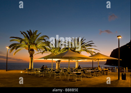 Terrasse d'un restaurant avec palmiers au coucher du soleil, Camara de Lobos, Madère, Portugal Banque D'Images