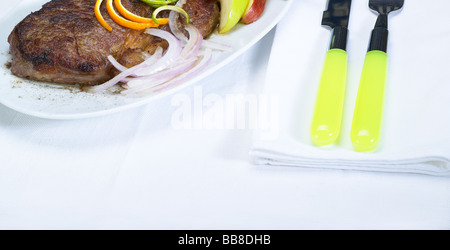 Boeuf juteux steak faux-frais grillé à l'orange et le zeste de citron sur le dessus et à côté de l'oignon Banque D'Images