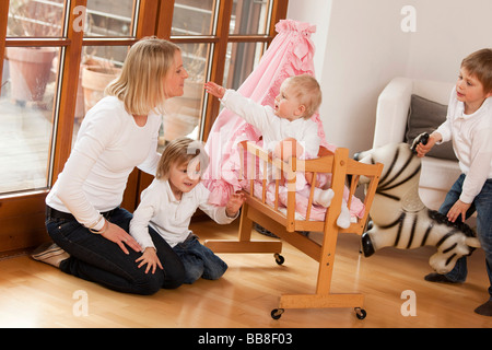 Mère de trois enfants, 1, 3 et 6 ans, jouant avec un landau de la pram Banque D'Images