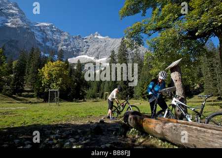 Alpinistes, homme et femme se reposant dans un puits, elle remplit sa bouteille de vélo, quartier de la forêt de Kleiner Ahornboden, Banque D'Images