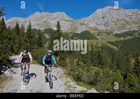 Riders vtt, hommes et femmes entre Karwendelhaus, alpine club house, et Kleiner Ahornboden Forest District, Hinterri Banque D'Images