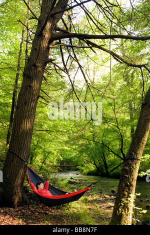 Woman relaxing in hammock par river - Pisgah Forest National - Brevard, Caroline du Nord. Banque D'Images