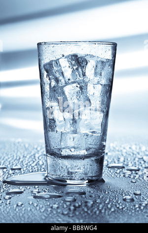 Grand tumbler rempli de glace placé sur une table métallique humide. Banque D'Images