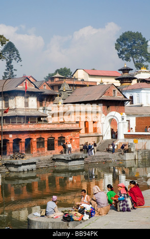 En deuil et de prêtre au temple de Pashupatinath temple avec un bûcher brûler de l'autre côté de la rivière Banque D'Images