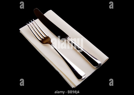 Fourchette et couteau en métal plaqué argent sur une serviette de table papier crème Banque D'Images