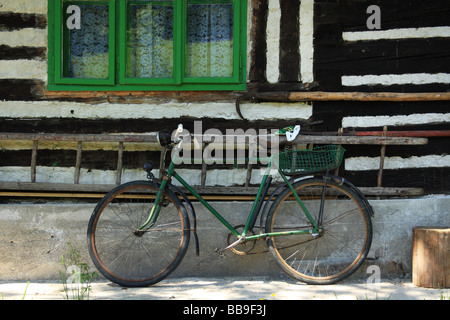 Un vieux vélo s'appuie contre le mur en bois d'une maison de montagne traditionnelle. République slovaque. Banque D'Images