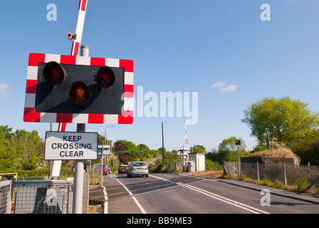 Une barrière automatique avec des feux d'avertissement sur un train de chemin de fer britannique voie traversant la rue avec panneau garder clair passage Banque D'Images