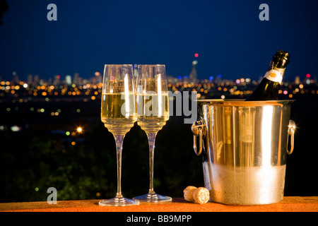 Bouteille de champagne et deux verres avec night skyline en arrière-plan avec ville iights Banque D'Images