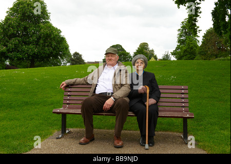 Les couples mariés âgés assis sur banc de parc Banque D'Images