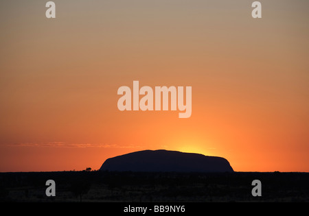 Le soleil se lève derrière Uluru (Ayers Rock). Le Parc National d'Uluru-Kata Tjuta, Territoire du Nord, Australie Banque D'Images