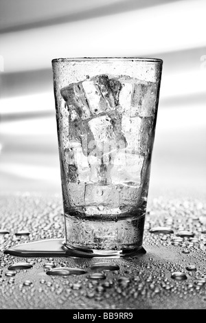 Boire dans un verre rempli de glace placé sur une table métallique humide. Banque D'Images