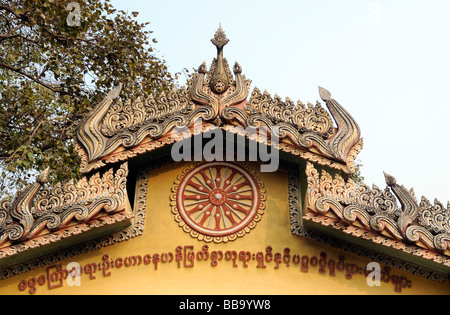 Passerelle ornementé à Sarnath bouddhistes avec la roue de la vie.L'arbre de la Bodhi, sacrée Fig (Ficus religiosa) Ficus en arrière-plan Banque D'Images