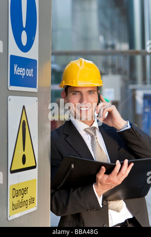 Gestionnaire d'un homme sur un site de construction portent un casque et à parler sur son téléphone Banque D'Images