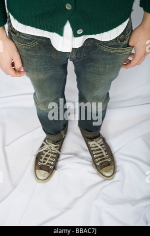 Un jeune homme habillé en jeans et chaussures de toile Banque D'Images