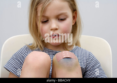 Une jeune fille avec un pansement sur son genou Banque D'Images