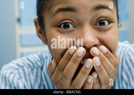 Une jeune femme couvrant sa bouche et rire Banque D'Images