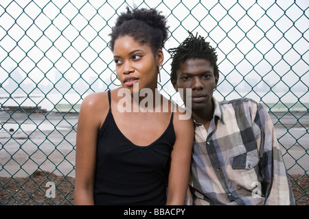 Un jeune couple devant une clôture de grillage simple torsion Banque D'Images