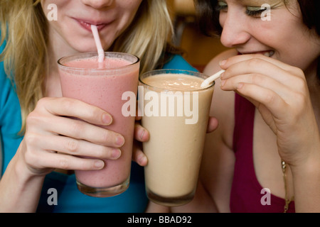 Détail de deux jeunes femmes de boire des smoothies de fruits Banque D'Images