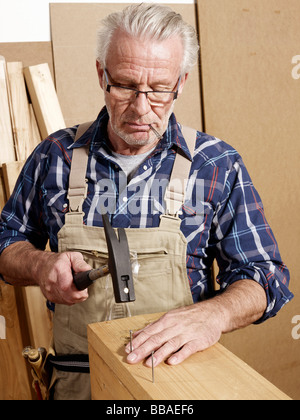 Un homme martelant des clous dans le bois Banque D'Images