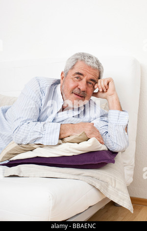 A senior man sitting on a couch Banque D'Images
