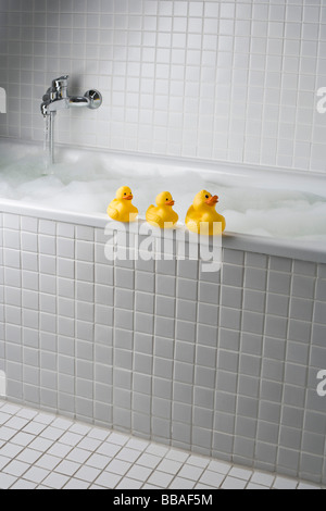 Un bain moussant avec des canards en caoutchouc sur le côté de la baignoire Banque D'Images