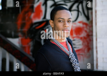 Portrait of a young man standing in front of graffiti sur un mur Banque D'Images