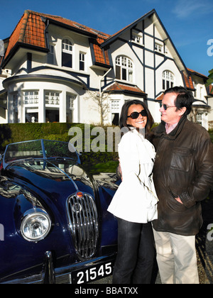 Couple devant leur maison et voiture Banque D'Images