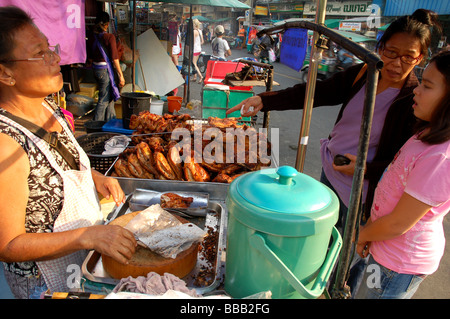 Dame thaïlandaise poulet grillé vente jambes dans Khao San Road, Bangkok, Thaïlande Banque D'Images