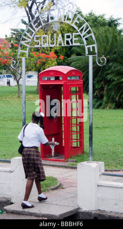 Jeune femme marche dernières vieux rouge téléphone britannique fort Independence Square St Kitts Basseterre Banque D'Images
