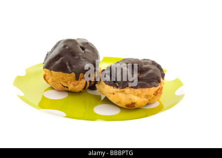 Choux à la crème fraîche enrobées de chocolat sur un fond blanc Banque D'Images