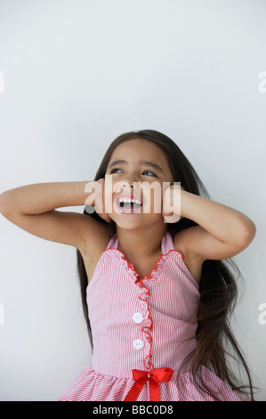 Une jeune fille porte sur ses oreilles avec ses mains Banque D'Images