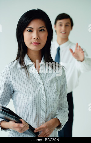 Une femme regarde la caméra comme son collègue essaie d'attirer son attention Banque D'Images