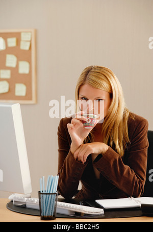 Une femme regarde la caméra comme elle boit une tasse de thé chinois Banque D'Images