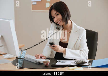 Une femme parle au téléphone pendant qu'elle est à l'œuvre Banque D'Images