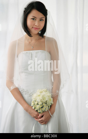 Une fiancée avec un bouquet de fleurs ressemble à l'appareil photo Banque D'Images