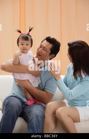 Mère et père avec petite fille, assise sur la table, heureux Banque D'Images