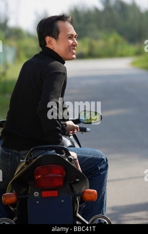 Homme assis sur la moto, à l'écart Banque D'Images