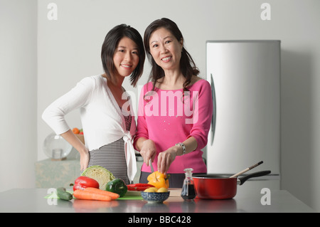 Mère et fille adultes dans la cuisine préparer un repas, looking at camera Banque D'Images