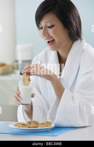 Femme dans la cuisine, cuisine de trempage en verre de lait, smiling Banque D'Images