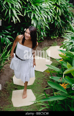 Jeune femme marchant dans un jardin tropical Banque D'Images