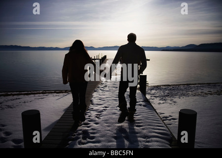 Couple walking on snowy pier at sunset Banque D'Images