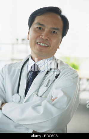 Doctor smiling at camera, les bras croisés Banque D'Images