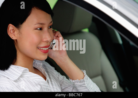 Businesswoman sitting in car using mobile phone Banque D'Images