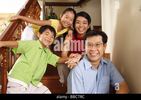 Famille avec deux enfants, assis sur les escaliers, smiling at camera, portrait Banque D'Images