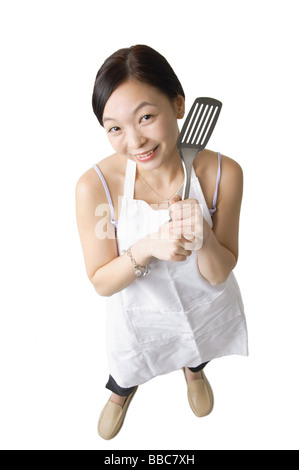 Woman in apron holding ustensile de cuisine Banque D'Images